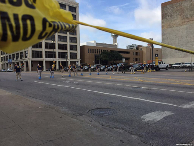 Law enforcement personnel investigating the crime scene, Dallas, Texas. Image via Wikipedia/ 