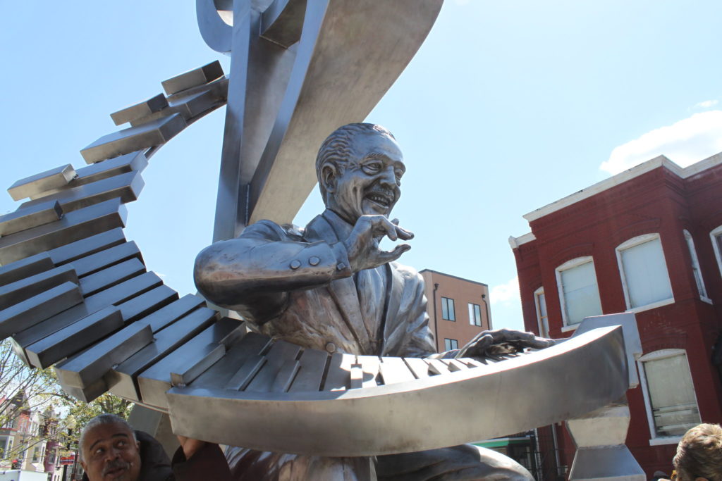 A silver statue of jazz musician Duke Ellington playing piano keys that spiral up into a treble clef